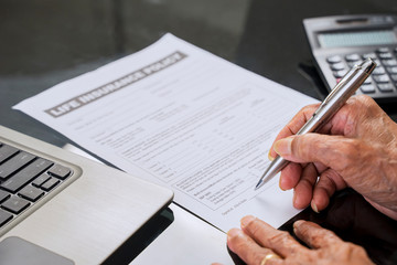 Senior man hand signing a life insurance form