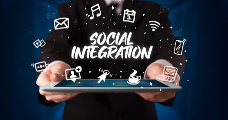 Young business person working on tablet and shows the inscription: SOCIAL INTEGRATION