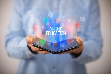 Young man holding a foldable smartphone with ONLINE EDUCATION inscription, educational concept