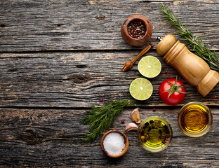 Tomato, lime, olive oil with spices  on wooden background. Top view. Rustic style.