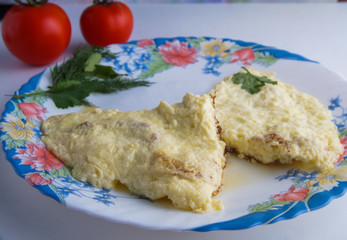 still life of omelet on a colorful plate and two tomatoes on a white background
