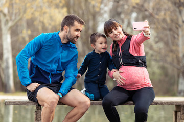 Obraz na płótnie Canvas Happy young family taking a selfie with the smartphone while enjoying the time together outdoor.