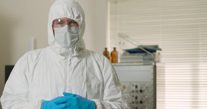 A doctor or other HCP in full PPE during the coronivirus epidemic looks at camera with copy space.