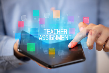 Young man holding a foldable smartphone with TEACHER ASSIGNMENT inscription, educational concept