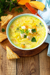 The concept of healthy and diet food. Pumpkin and turkey soup with cream on a rustic wooden table. Copy space.