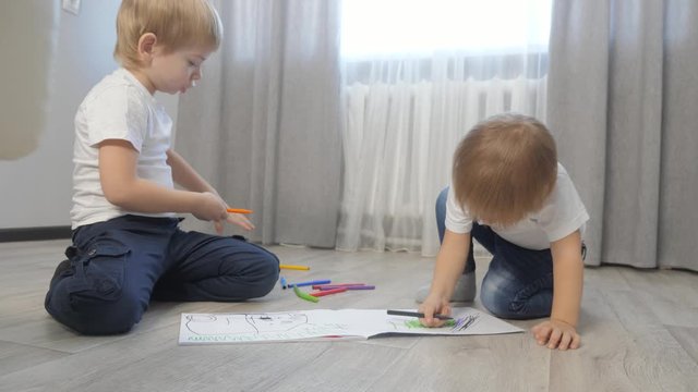 children draw with felt-tip pens in an album. little boy and girl concept childhood brother and lifestyle sister play paint on the floor with colored markers