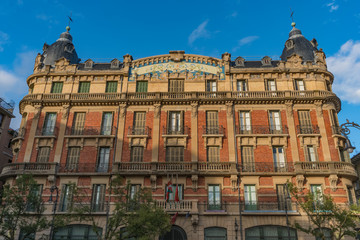 Obraz premium Old library building in Pamplona in Navarra, Spain, located in Plaza San Francisco, with a red brick facade with a blue mosaic in the center, two blue tile domes on the sides stone balconies and trees