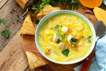 The concept of healthy and diet food. Pumpkin and turkey soup with cream on a rustic wooden table. Copy space.