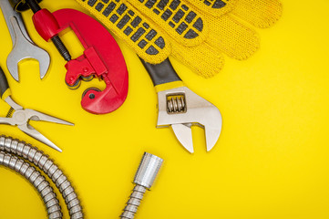 Plumbing tools and gloves for connecting water hoses on a yellow desktop
