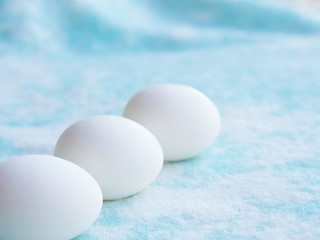 Easter uncolored white and brown eggs on a light blue background with flowers decoration