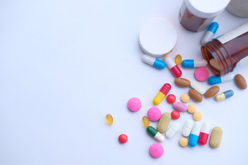 colorful pills spilling from container on white background 
