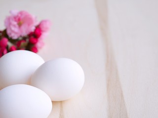 Easter uncolored white and brown eggs on a light blue and wooden background with flowers decoration