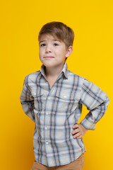 Cute little smiling boy in a tuxedo shirt Isolated on a yellow background.