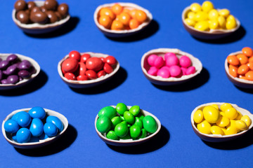 A pattern of halves of chocolate eggs filled with colored jelly and shot closeup on a blue background. Sweet photo for your tasty design.