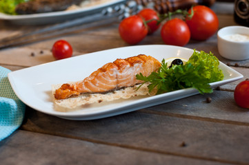 food photo steamed fish with vegetables on a white plate with onion halves tomatoes green branches on a blue wooden background