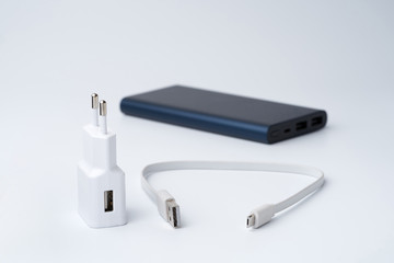 White USB power adapter, cable and blue power bank for divice isolated on a white background.