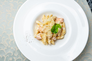 Penne with salmon on white plate