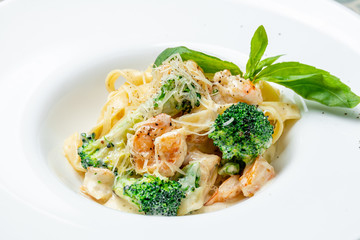 Pasta fettuccine with shrimps and broccoli on white plate