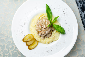 Stroganoff on white plate with mashed potatoes and basil
