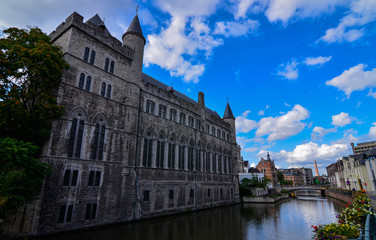 Fototapeta na wymiar Ghent, Belgium, August 2019.Geraard de Duivelstraat Castle. The main facade overlooks the canal: it is an example of the medieval buildings of the city. Blue sky with white clouds.