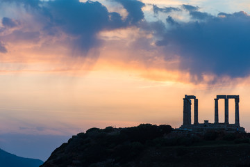 The famous ancient temple of Poseidon in Cape Sounio near Athens Greece during sunset with beautiful cloud formations and warm pastel colors