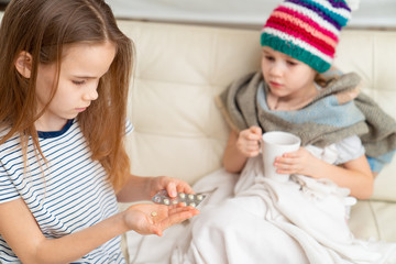 big sister giving medicine of sick younger 