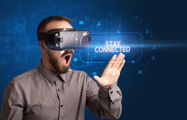 Businessman looking through Virtual Reality glasses with STAY CONNECTED inscription, social networking concept