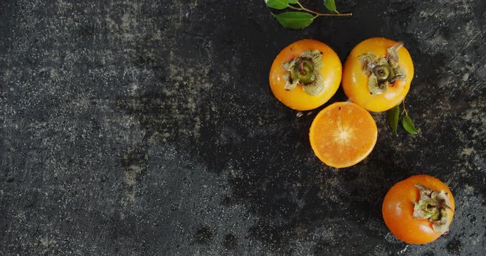 Fresh persimmons falling water drops. Top view.
