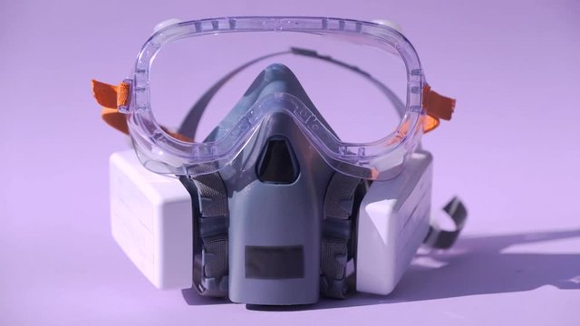 Half mask respirator with special goggles on a pink background.