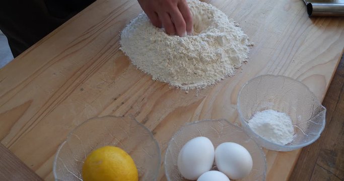 Young mother cooking biscuits with her two kids, mixing flour with eggs, sugar, butter, lemon