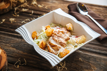Closeup on caesar salad in white plate on the wooden table, horizontal format