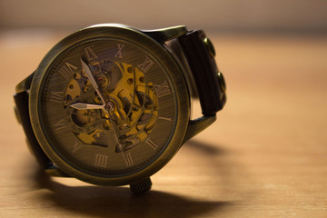 Watch on a blurry surface, a vintage wristwatch with a brown and gold clock hand, with a brown/white background