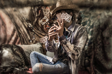 close up portrait of  guy in cowboy hat. boho style background. a guy with playing cards. illusionist