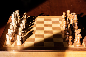 Close up image of chess board and chess pieces with lopsided sunlight and shadows