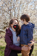 Fototapeta premium Mother with a small son in protective masks went for a walk from home. The city is in quarantine.