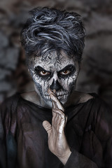 Close up studio portrait of man with skull face painting. Emotional beautiful guy. Professional Halloween makeup