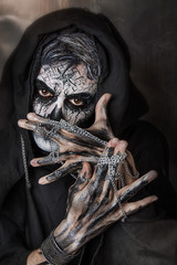 Close up studio portrait of man with skull face painting. Emotional beautiful guy. Professional Halloween makeup