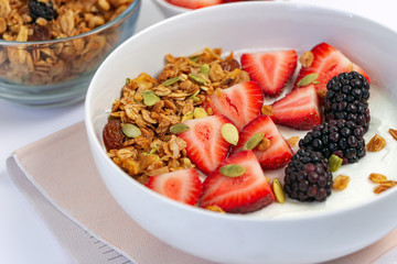 Homemade granola with bowl of Greek yogurt and fresh berries for breakfast.