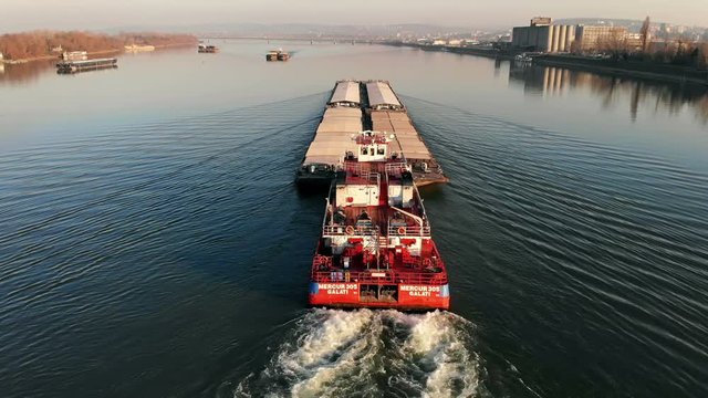 Tugboat pushing a barge on the river, drone video