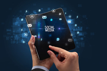 Businessman holding a foldable smartphone with SOCIAL MEDIA inscription, social networking concept