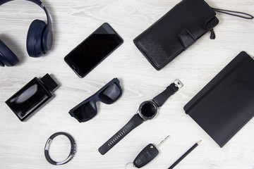 Background men's accessories lie on a wooden background. Black glasses, watch, notebook, wallet are on a light background. Objects close-up, top view