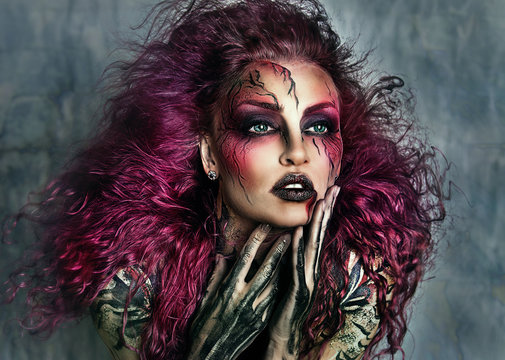 Close up portrait of sexy beautiful witch with Halloween makeup. Beautiful flying pink hair. Professional creative face painting	
