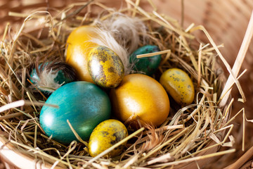 Easter composition. Cute painted easter eggs  are placed on nice haystack from dried straws and inside wicker basket. Greeting card concept.