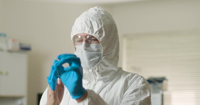 A tired doctor or healthcare employee removes his PPE after a long shift dealing with contagious patients dealing with or exposed to the coronavirus.