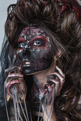 close up portrait of terribly beautiful girl with Halloween skull makeup. Black face painting. lush hair