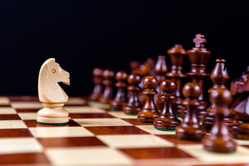 white chess knight against black pieces © Chabanenko Maksim