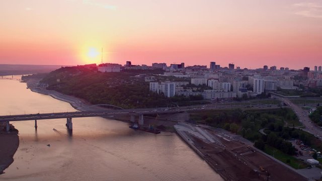 Ufa city Main bridge with car traffic through Belaya river in Bashkortostan with view to Cultural center of the city at beautiful sunset at background