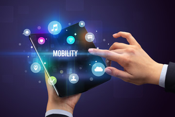 Businessman holding a foldable smartphone with MOBILITY inscription, social media concept