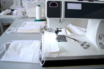 Herz aus Garn auf der Nähmaschine. Herstellung von Mundschutzmasken aus Baumwollstoff in einer Manufaktur um die Gesundheit vor einer Infektion mit dem Coronavirus zu schützen