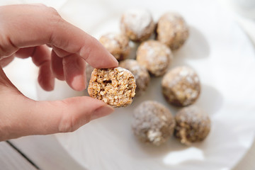 step by step visual instruction how to make energy balls. step 3, form balls. protein balls making. hand holding ball bitten.